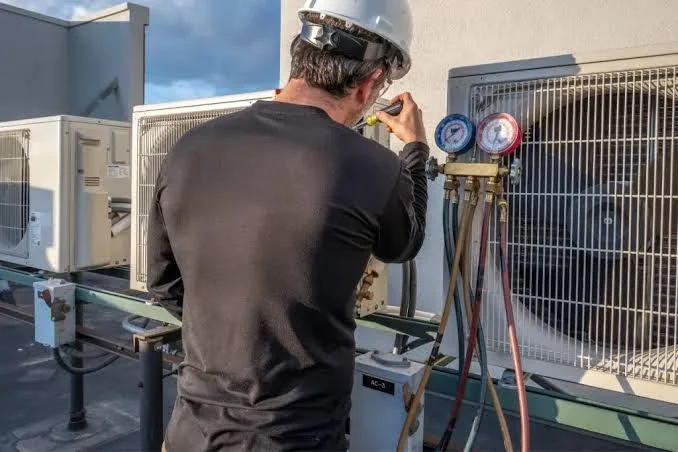 Illustrative technician using pressure gauges while servicing outdoor HVAC equipment